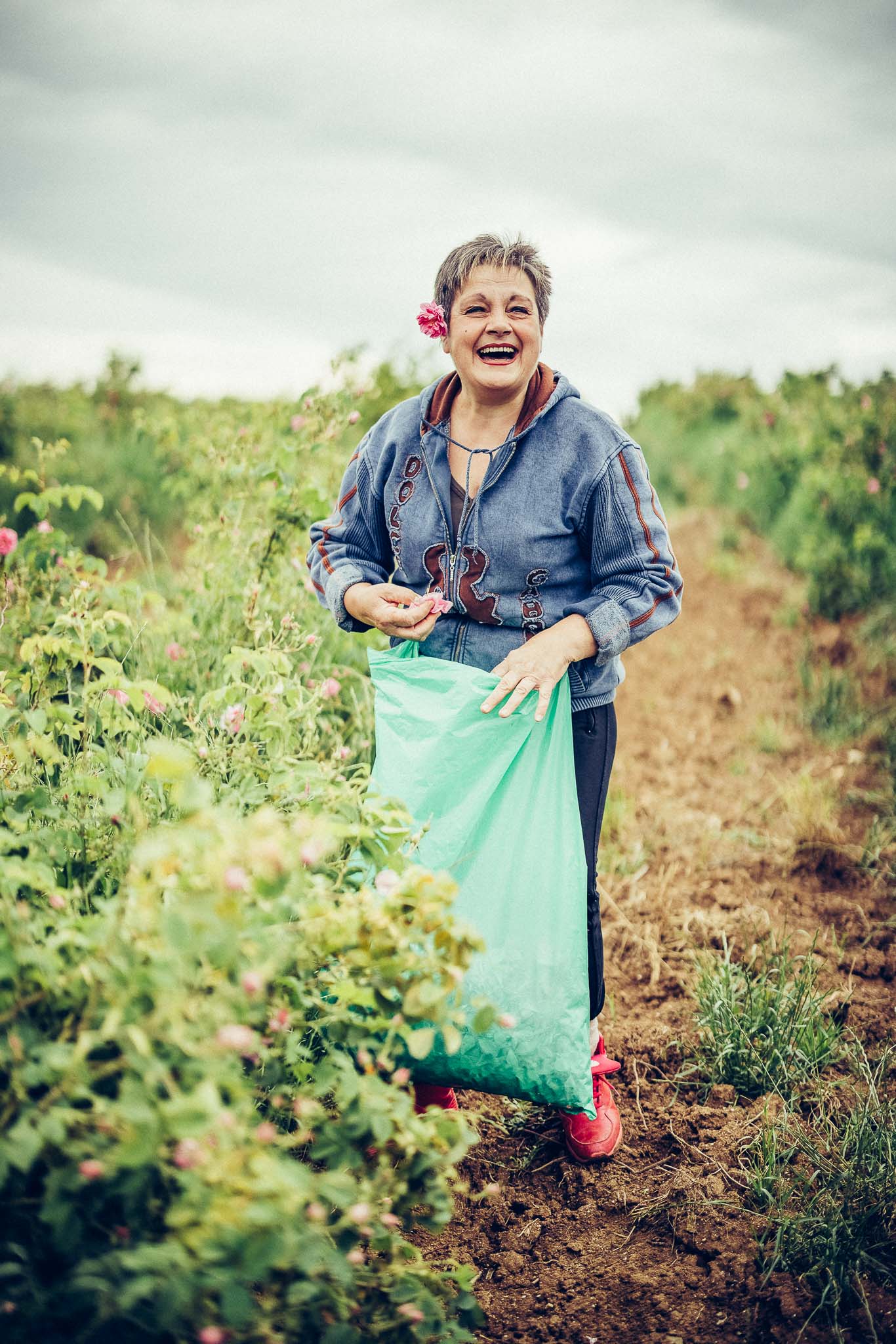 A woman holding a green bag in a rose field.