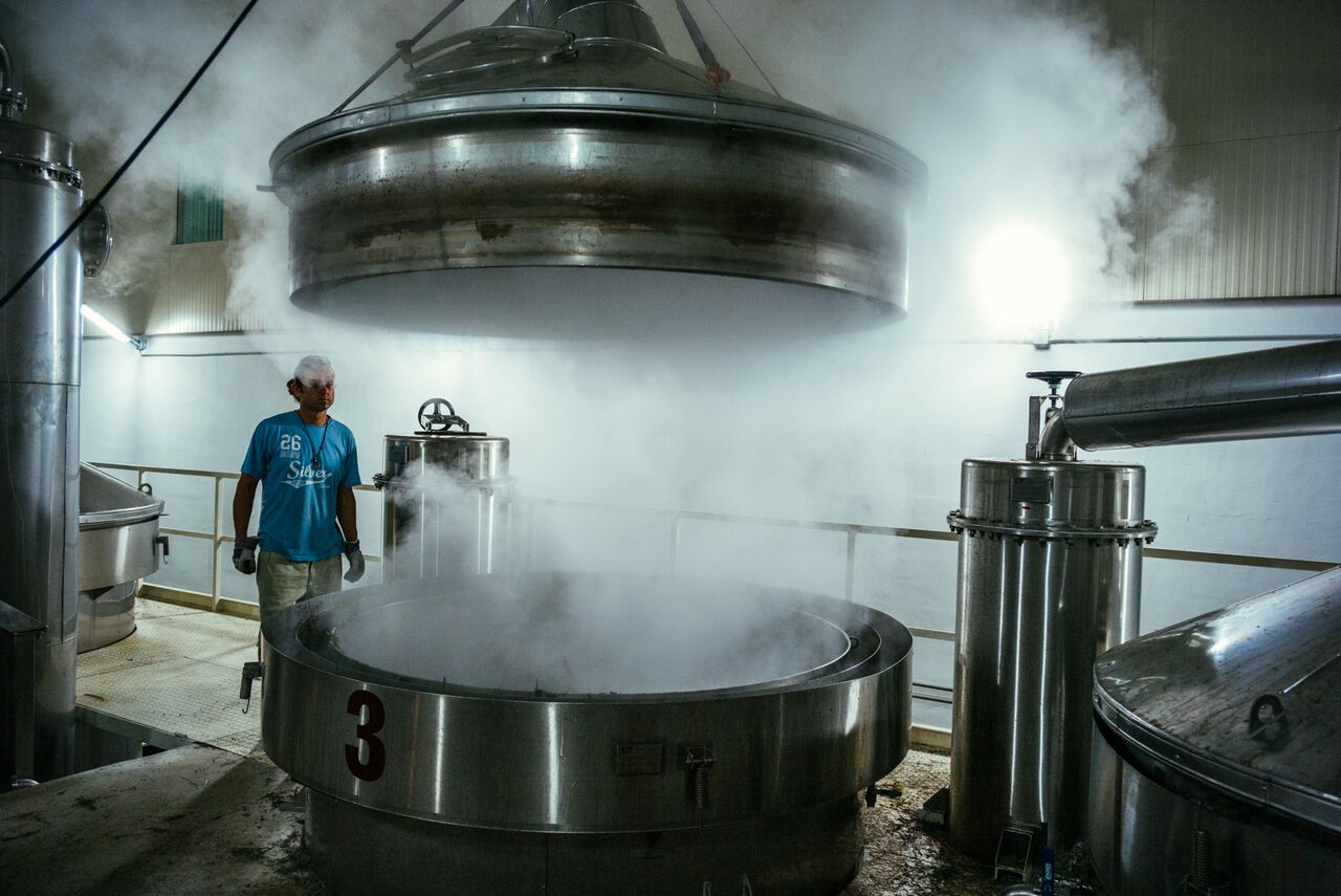 A man standing next to a steaming pot in a Bulgarian rose factory.