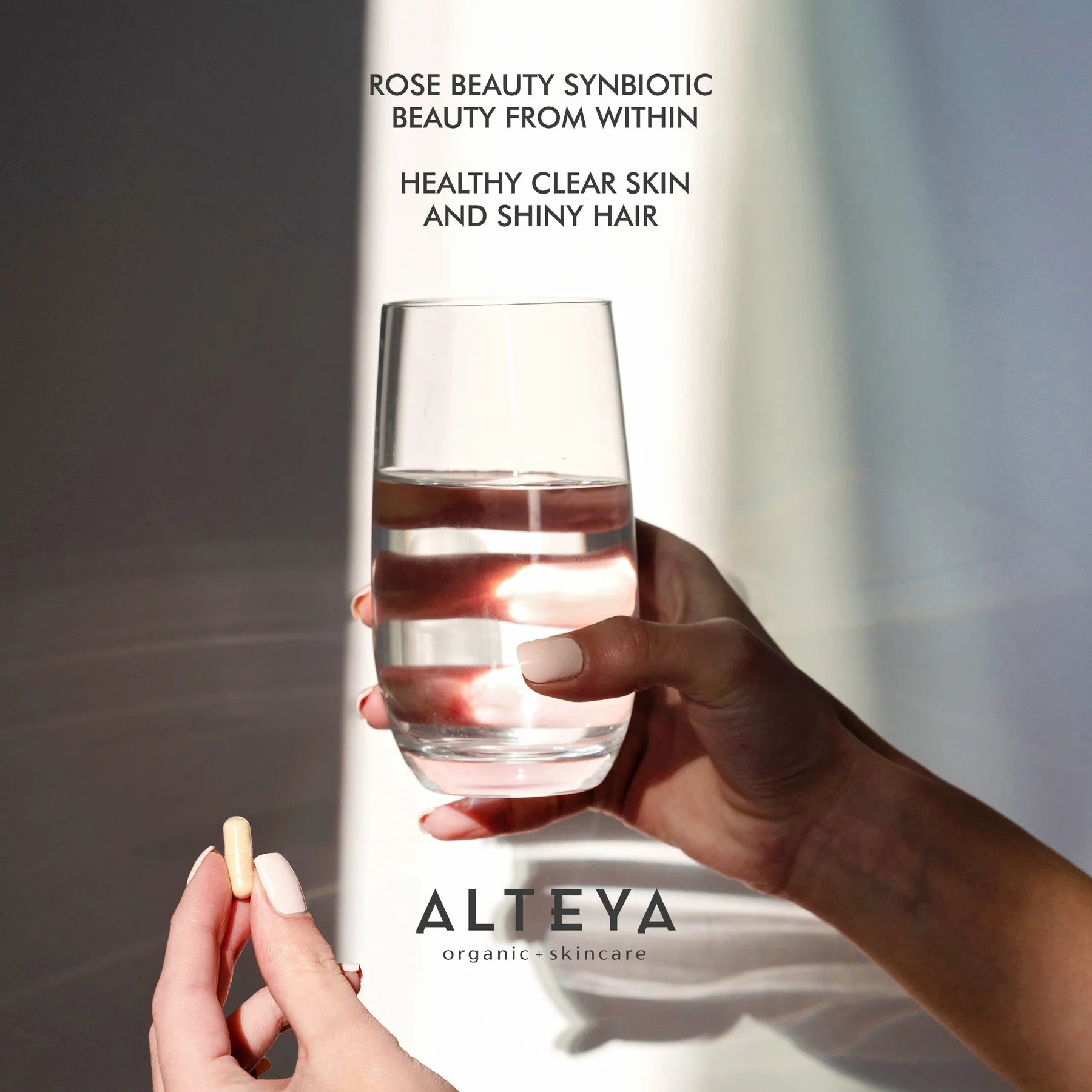 A woman holding a glass of water, emphasizing the synergy between gut health and skin appearance, with Rose Beauty Prebiotic and Probiotic - Synbiotic Skin & Metabolism Vegan Organic Supplement.