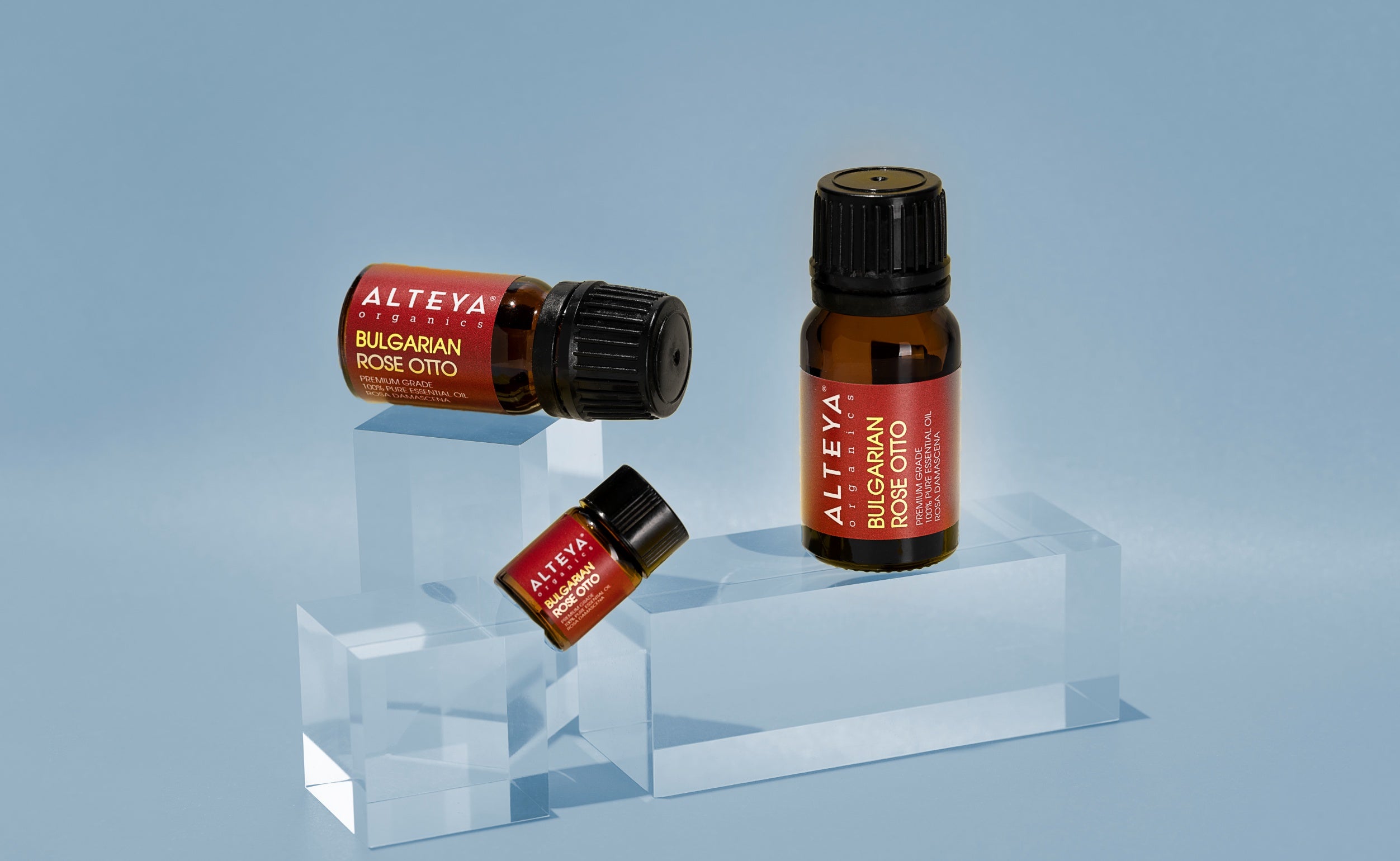 Two bottles of essential oils infused with the exquisite fragrance of rosa damascena, set against a tranquil blue background.