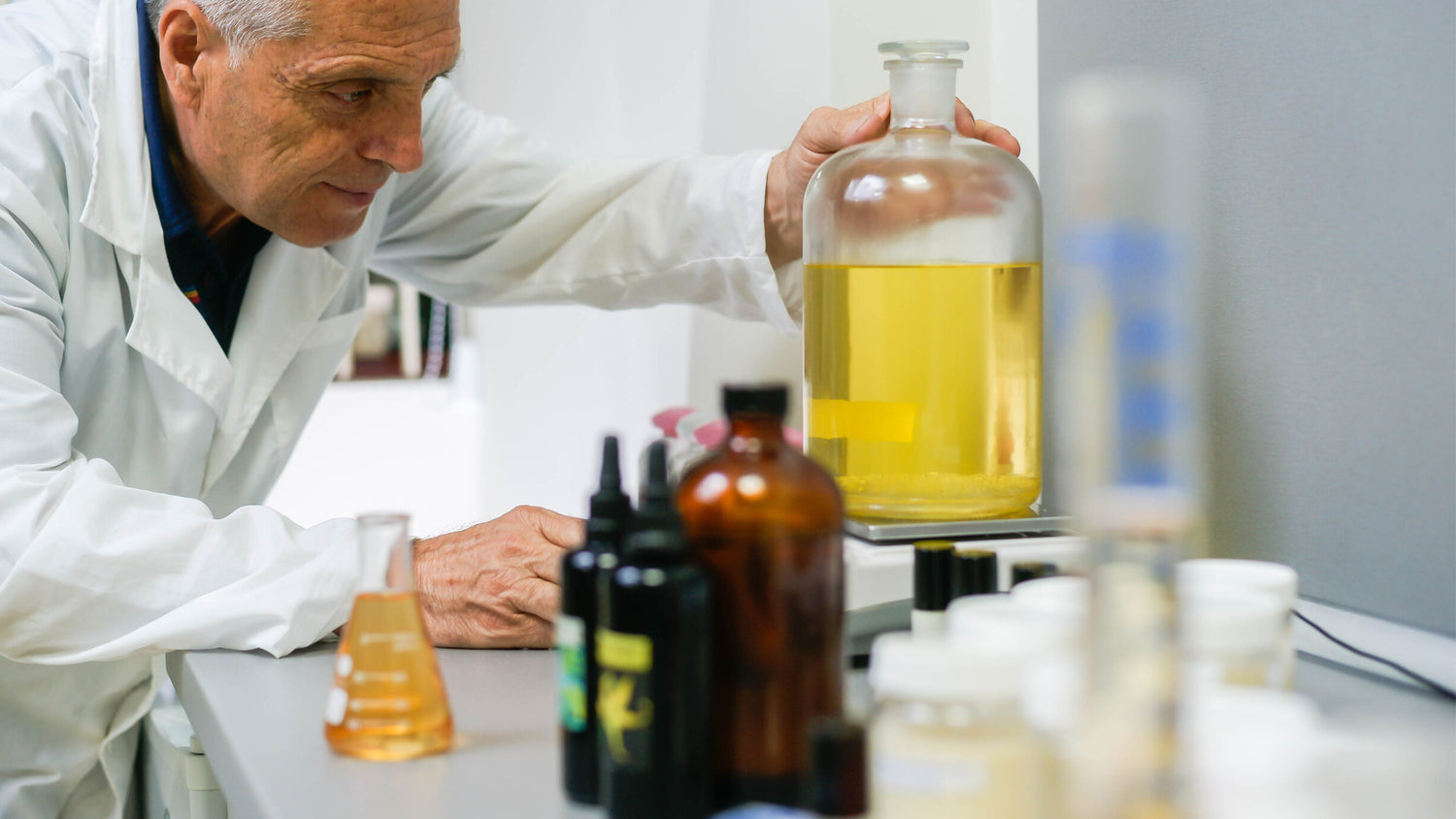 A man in a lab studying a bottle of liquid made from rosa damascena.