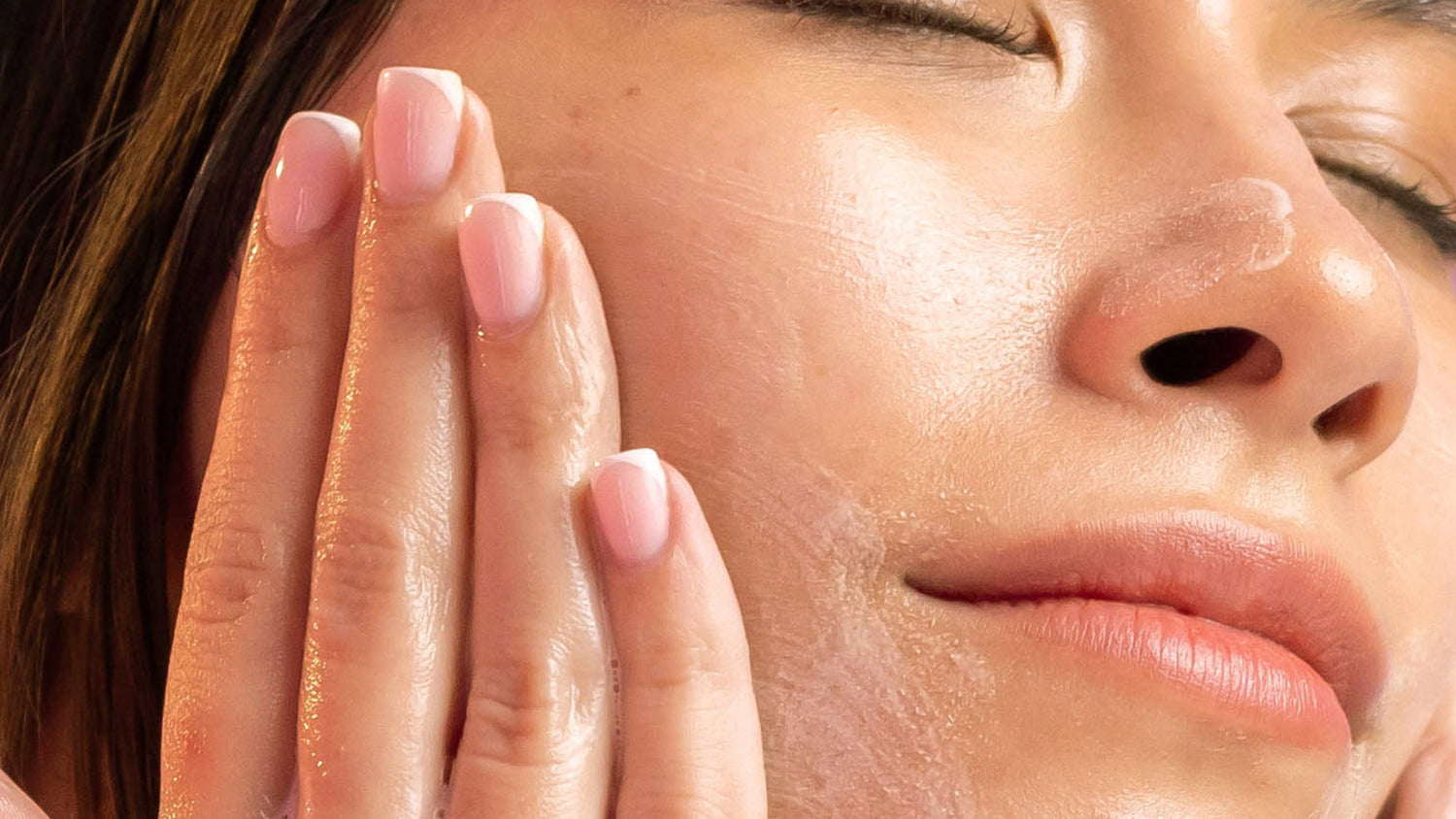A woman is using a facial cleanser infused with Bulgarian rose extract on her face.