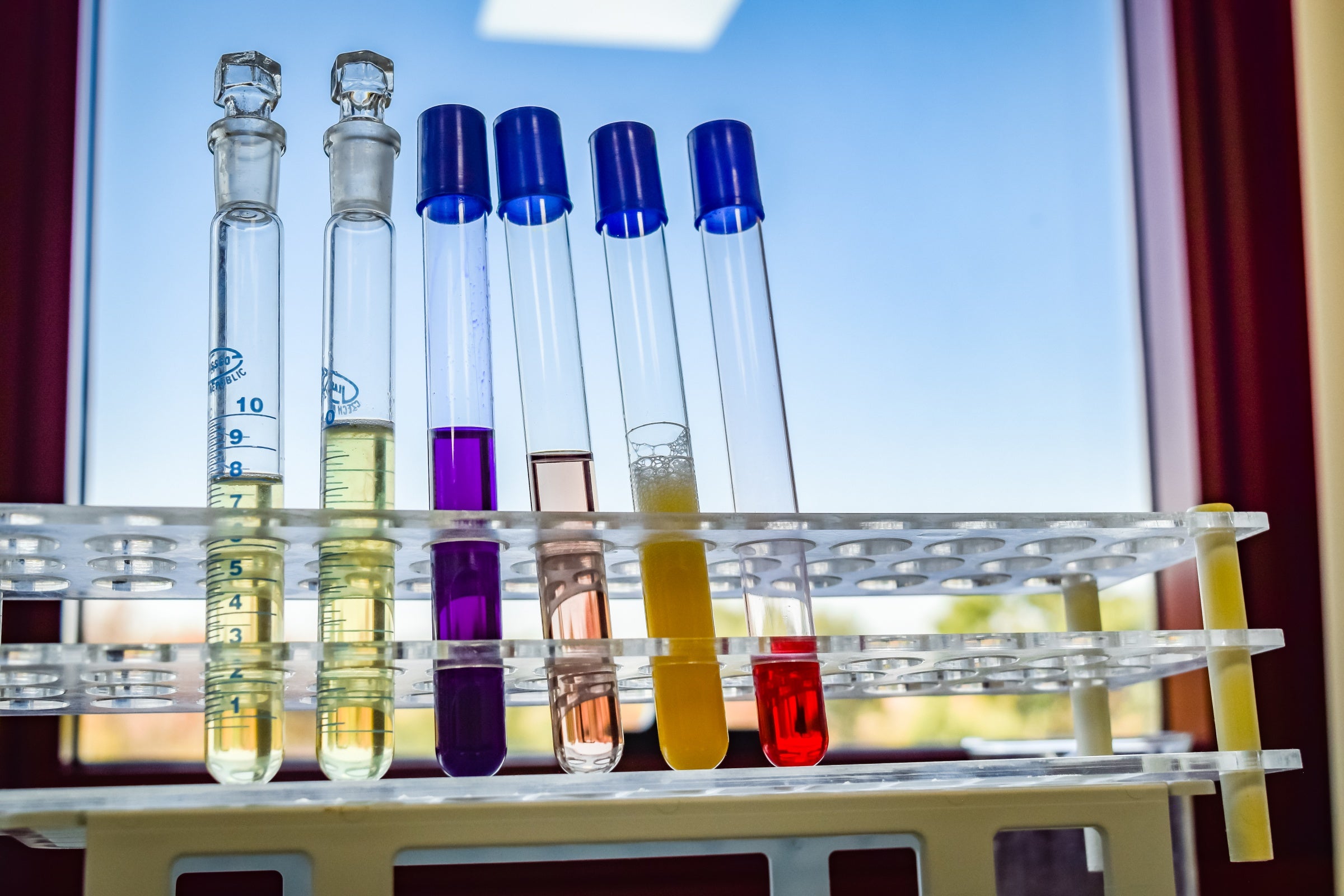 A group of test tubes containing Bulgarian rose liquids in front of a window.