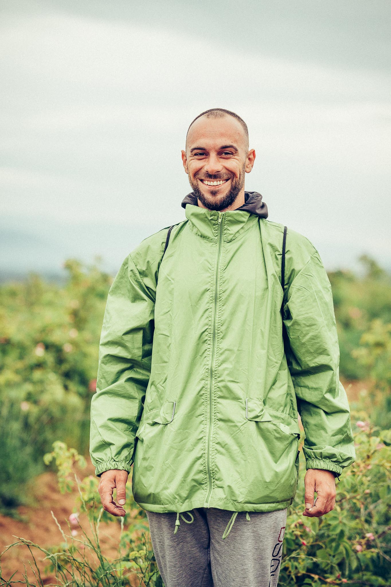 A man in a green jacket standing amidst the breathtaking Bulgarian rose fields.