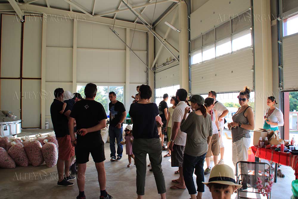 A group of people standing in a warehouse surrounded by boxes of Bulgarian rose abundance.