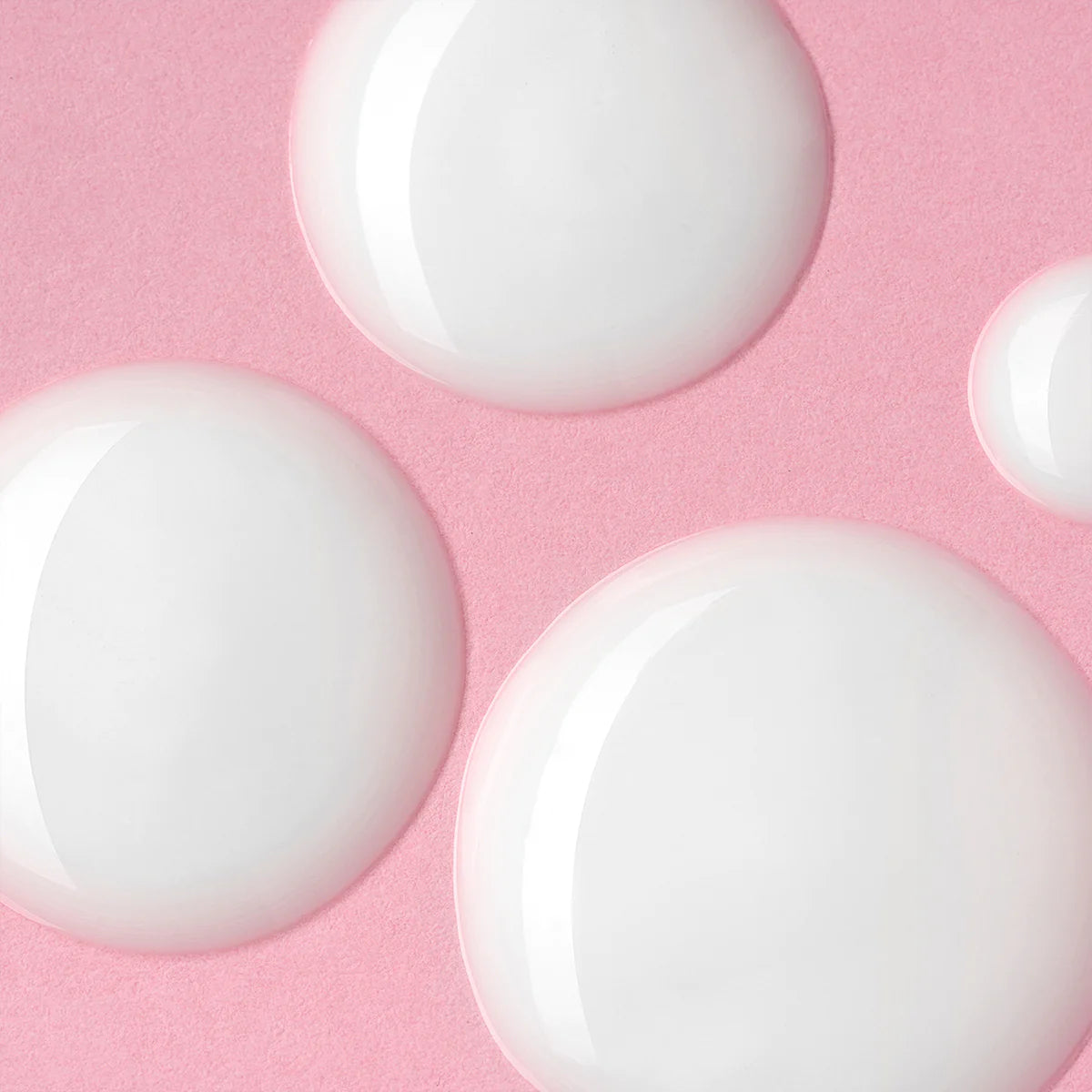 A group of white circles on a pink background, resembling Iridescent Light Serum Luminous Rose drops for the skin.