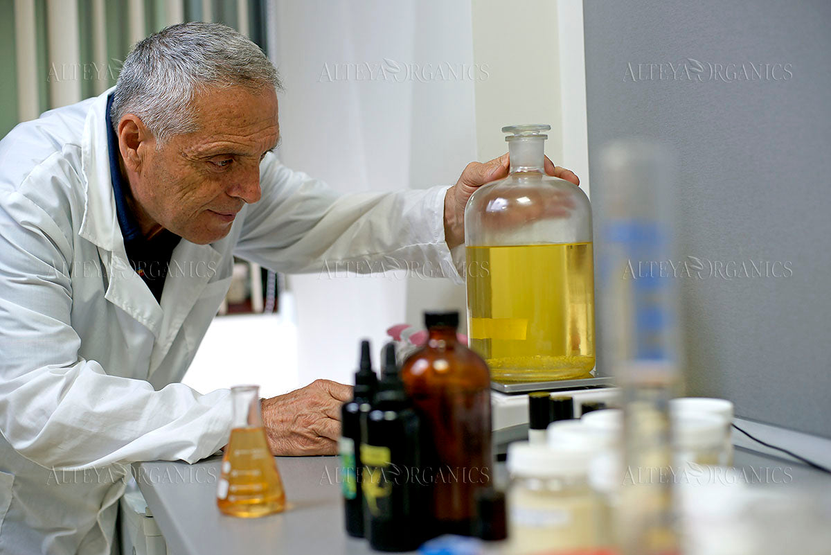 A man in a lab coat studying a bottle of liquid containing Bulgarian rose.