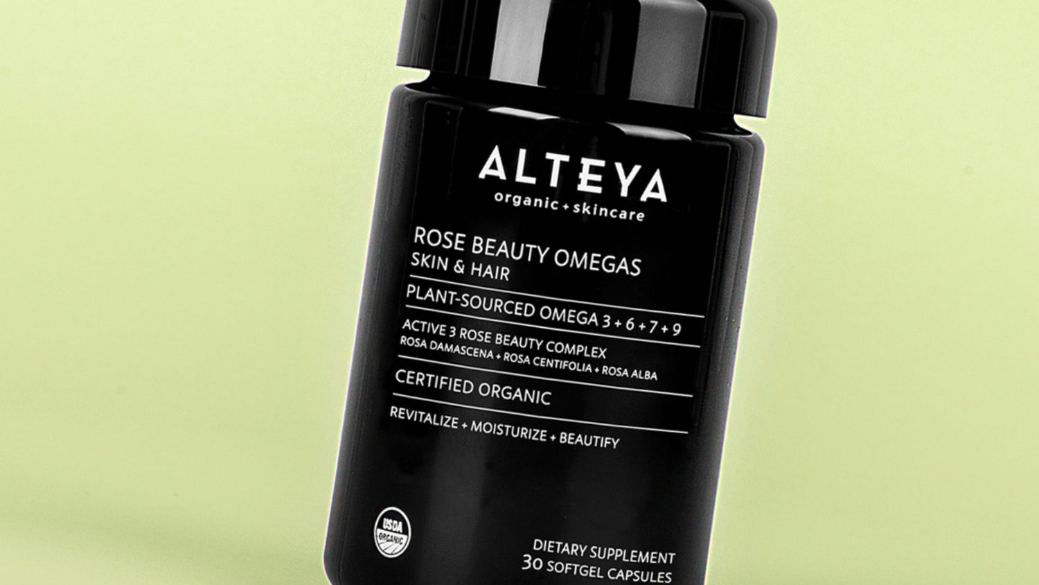 A bottle of alteya rose beauty formula with rosa damascena on a green background.