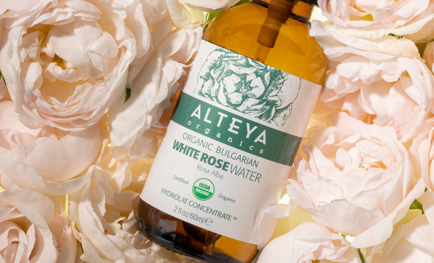 A bottle of Alteya organic face oil surrounded by Bulgarian roses.